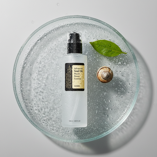 COSRX Advanced Snail 96 Mucin Power Essence lifestyle flat lay on dewy glass surface